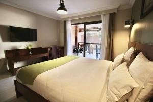 a bedroom with a large white bed and a balcony at La Colongette in Antsirabe
