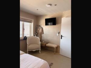 a bedroom with a bed and a chair and a window at Gastenverblijf de paddestoel in Urk