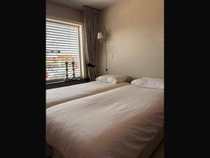 two beds in a room with a window at Gastenverblijf de paddestoel in Urk