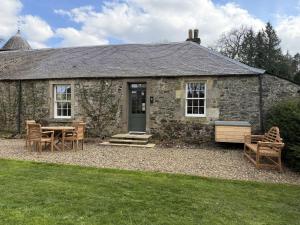 a stone house with a table and chairs in front of it at Barns Studio in Peebles