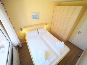 a small bedroom with a white bed and a door at Appartement-124 in Westerland