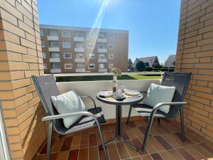 a small table and chairs on a balcony with a window at Appartement-124 in Westerland