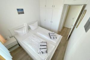 a white bedroom with a bed with two towels on it at Appartement-162 in Westerland