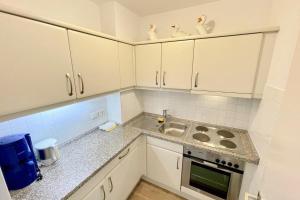 a kitchen with white cabinets and a sink at Appartement-162 in Westerland