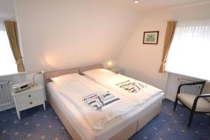 a bedroom with a bed and a chair and a window at Haus-Neumann in Westerland