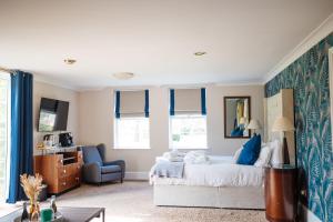 a bedroom with a bed and a blue chair at Woodland Manor Hotel in Bedford