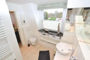a white bathroom with a toilet and a window at Syltstyle-12 in Tinnum +16 photos