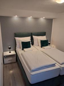 a bedroom with two beds with white sheets and green pillows at House Josipa in Rakovica