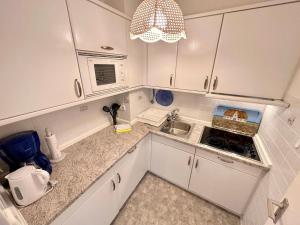 a kitchen with white cabinets and a sink and a microwave at Ferienwohnung-20-A139 in Westerland +4 photos