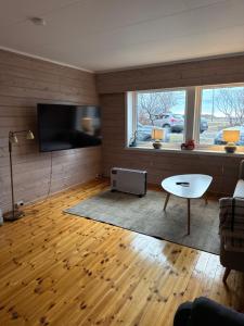 a living room with a couch and a table and a tv at Sissels Guesthouse in Andøya