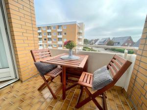 a wooden table and two chairs on a balcony at Ferienwohnung-20-A139 in Westerland