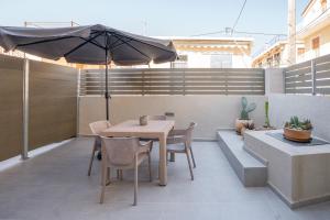 a patio with an umbrella and a table and chairs at Agora Luxury Suites in Lixouri
