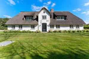 a large white house with a thatched roof at Carolinenhof-1 in Tinnum