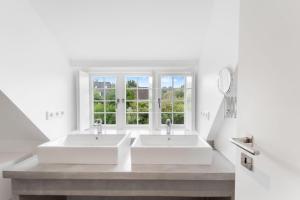 two sinks in a white bathroom with a window at Carolinenhof-1 in Tinnum +40 photos
