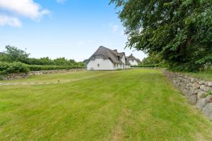 a house in a field with a stone wall at Carolinenhof-2 in Tinnum
