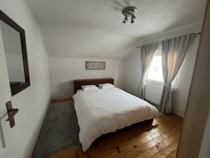 a bedroom with a white bed and a window at Kuća za odmor IVKOVIĆ in Kupres