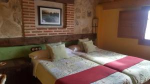 a bedroom with two beds and a brick wall at Casa El Pajar De Tasio in San Miguel del Pino