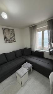 a living room with a black couch and a window at Lili's Sea View in Budva