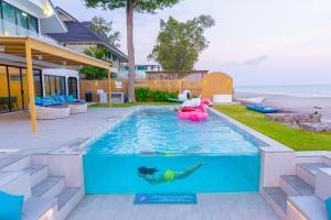 a person in a pool with a float in the water at Pailay Beachfront Villa Cha-Am in Ban Bang Ket