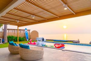 a patio with a swimming pool with rattan chairs and a swimming pool at Pailay Beachfront Villa Cha-Am in Ban Bang Ket