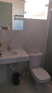 a bathroom with a toilet and a sink and a mirror at Casa da Dinda 203 in Rio das Ostras +3 photos