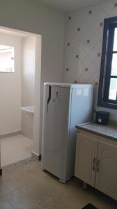 a kitchen with a white refrigerator in a room at Casa da Dinda 203 in Rio das Ostras