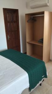 a bedroom with a bed with a green blanket on it at Casa da Dinda 203 in Rio das Ostras