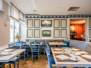 ein Restaurant mit Holztischen und blauen Stühlen in der Unterkunft PLAZA Premium Sylt in Wenningstedt-Braderup