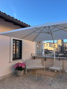 a large umbrella on a patio with two chairs and a table at Cavour Apartment in LʼAquila