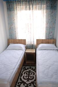 two beds in a small room with a window at Central Guest House Karakol in Karakol +18 photos