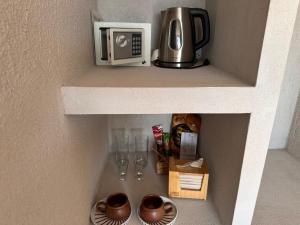 a shelf with a microwave and glasses on it at Perla Roca Hotel Boutique - Beach Front in Santa Marta