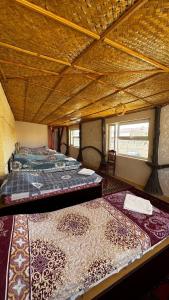 a group of beds in a room with wooden ceilings at Deshon Qala Guest House in Khiva