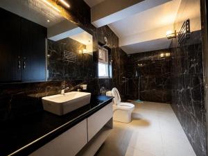 a black bathroom with a sink and a toilet at Balcony in the Clouds - Himalayan Views, Sunset in Rāmgarh