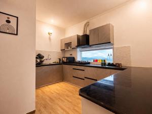 a kitchen with a counter top and a large window at Balcony in the Clouds - Himalayan Views, Sunset in Rāmgarh