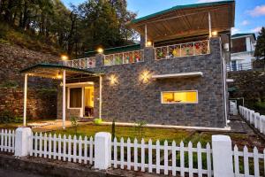 a brick house with a white fence in front of it at Balcony in the Clouds - Himalayan Views, Sunset in Rāmgarh +19 photos