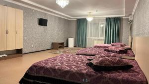 a large bedroom with two beds and a television at Акерке Балхаш in Balqash