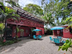 a red building with blue chairs and umbrellas at Ocean Breeze Beach Front Apartment with AC in Puerto Viejo