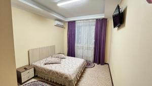 a bedroom with a bed and a window with purple curtains at Акерке Балхаш in Balqash