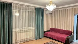 a living room with a red couch and a chandelier at Акерке Балхаш in Balqash