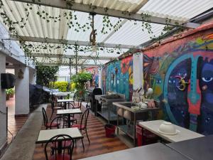 a restaurant with tables and chairs and graffiti on the wall at Anys Hostal in Mexico City