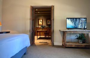 a bedroom with a bed and a desk with a television at Penny Royal Guest Cottages in Somerset West