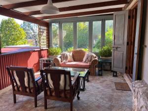a screened in porch with a couch and a table at Penny Royal Guest Cottages in Somerset West