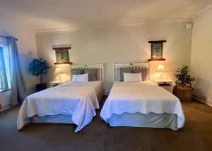 a bedroom with two beds with white sheets and lamps at Penny Royal Guest Cottages in Somerset West