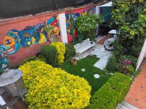 a garden with a bench and a painting on a wall at Anys Hostal in Mexico City +8 photos