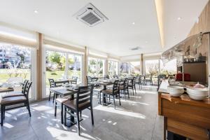 a dining room with tables and chairs and windows at Hôtel de France Contact-Hôtel in Évian-les-Bains +12 photos