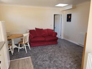 a living room with a red couch and a table at Pebble Beach, ground floor 1 bedroom flat in Chichester