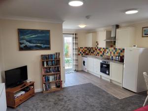 a kitchen with a refrigerator and a tv in a room at Pebble Beach, ground floor 1 bedroom flat in Chichester