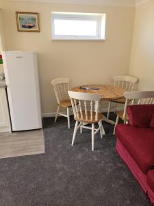 a dining room with a table and chairs and a refrigerator at Pebble Beach, ground floor 1 bedroom flat in Chichester +7 photos