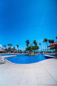 a large swimming pool with palm trees in the background at Maceió Atlantic Suites in Maceió