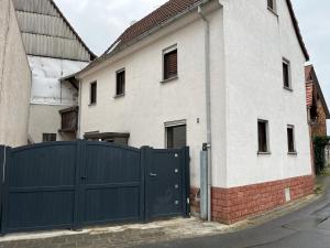 a white house with a blue gate in front of it at Gemütliche Wohnung mit WLAN, TV und Parkplatz in Groß-Umstadt